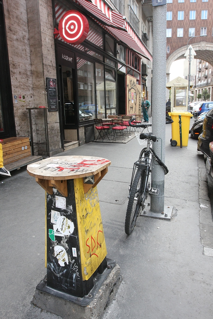 A smal table in front of Cafe Központ, Budapest by Architecture Uncomfortable Workshop