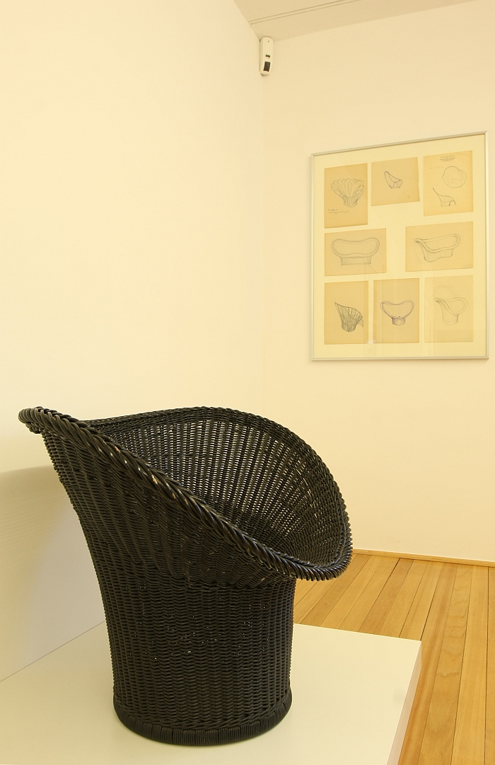 The E20 Korbsessel, in front of sketches of further wicker chairs, as seen at, Der Stuhl des Architekten - Sitzmöbel von Egon Eiermann, Ungers Archiv für Architekturwissenschaft Cologne