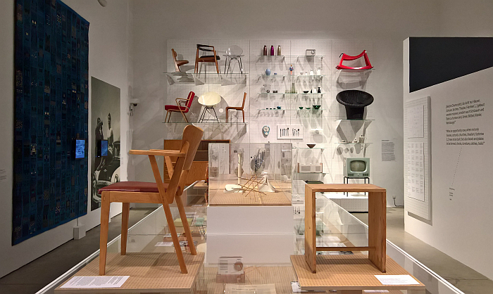 Two school chairs: the Seminarstuhl by Selman Selmanagic, Herbert Hirche & Liv Falkenberg for Deutsche Werkstätten Hellerau (l) and the Ulmer Hocker by Hans Gugelot, Max Bill and Paul Hildinger (r) in front of a wall of post-War doemstic design from West Germany and East Germany, as seen at German Design 1949–1989. Two Countries, One History, Vitra Design Museum, Weil am Rhein