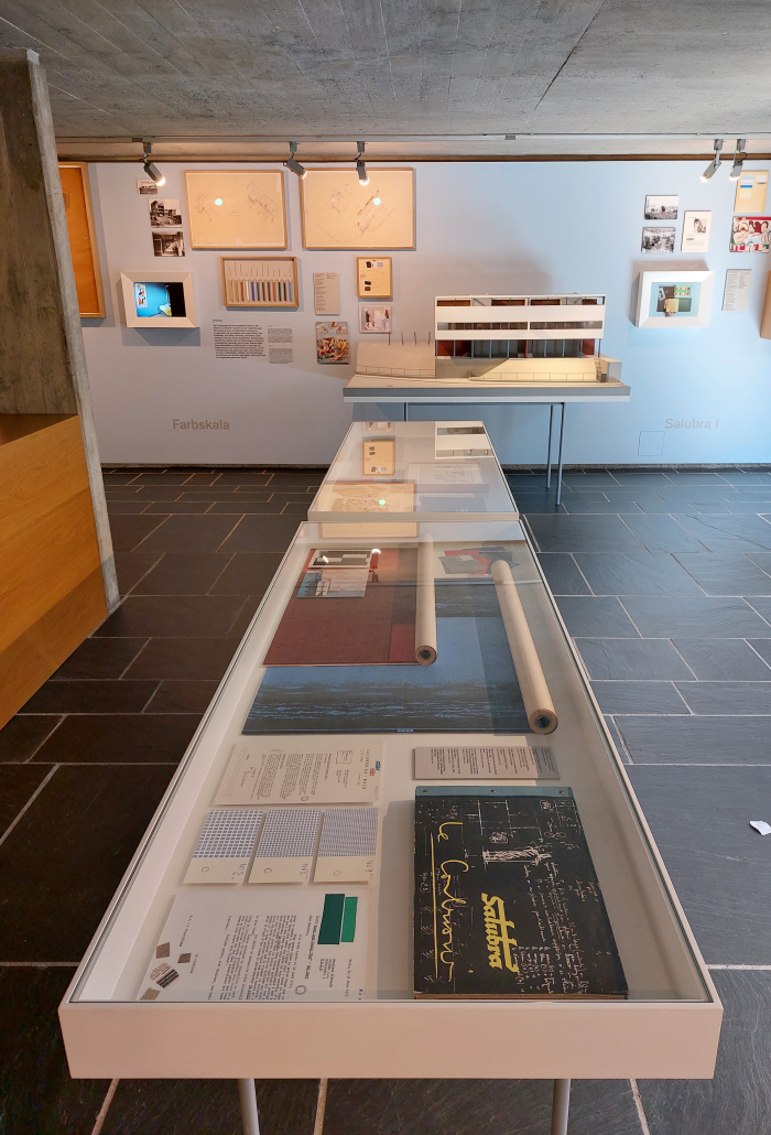 A view across items related to Le Corbsuier's cooperation with Salubra and towards a model of his and Pierre Jeanneret’s semi-detached house for the 1927 Weissenhofsiedlung building exhibition in Stuttgart, as seen at Le Corbusier and Color at the Museum für Gestaltung, Pavillon Le Corbusier, Zürich