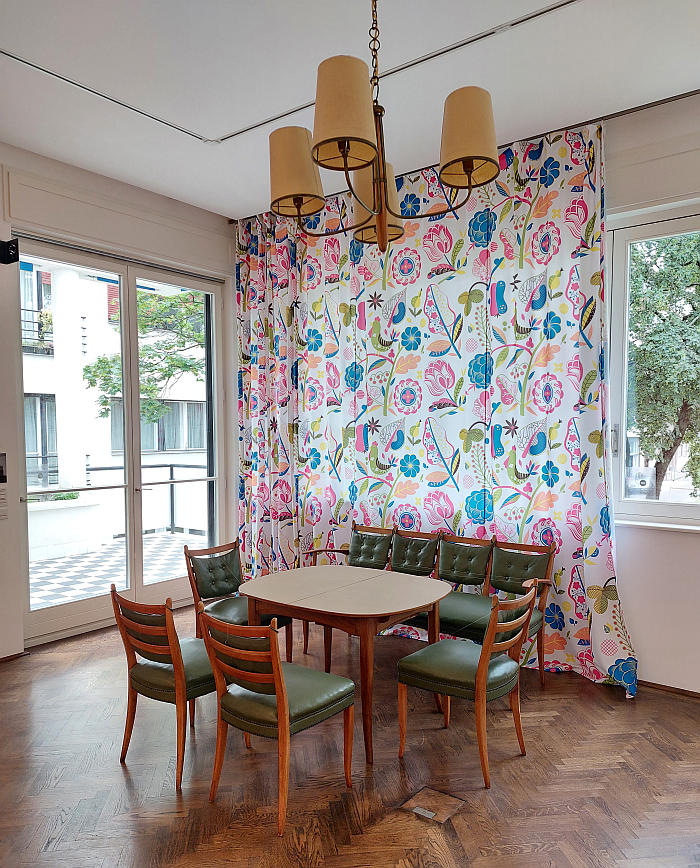 The Kaesz/Lukáts' dining table, chairs and bench in front of curtains featuring the 1936 pattern Napraforgó by Lukáts Kató, as seen in Kaesz Homes 1925-1960. The homes of designer couple Kaesz Gyula and Lukáts Kató, Walter Rózsi Villa, Budapest